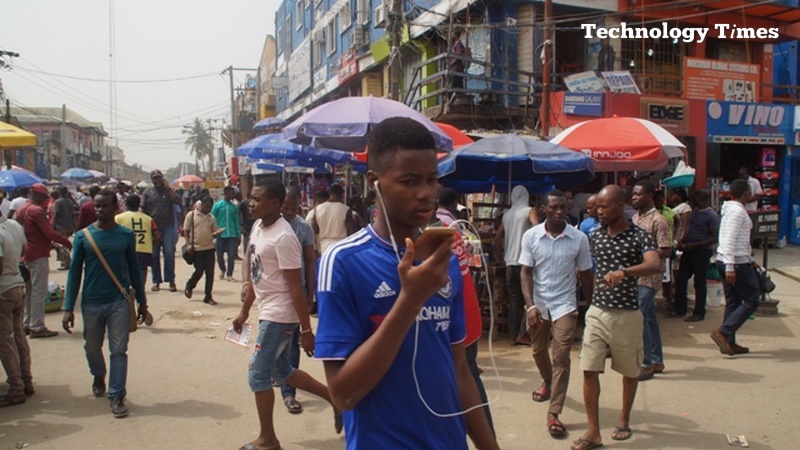 Technology Times file photo shows a young man seen using a mobile phone walking inside Computer Village in Ikeja, Lagos.